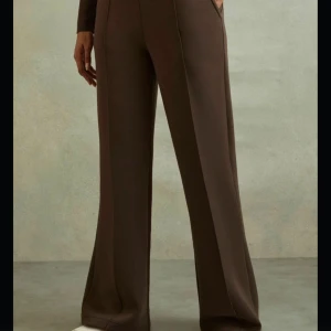 Bruna vida mjukisbyxor - Säljer ett par bruna mjukisbyxor med breda, vida ben och hög midja. Byxorna har en avslappnad passform och är perfekta för en chill och bekväm stil. Tillverkade i mjukt material som känns skönt mot huden.