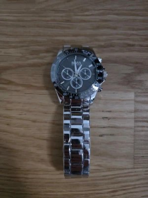 Silvrig Hugo Boss klocka svart urtavla - En stilig silvrig Hugo Boss klocka med svart urtavla och silverfärgat armband. Helt ny med plast och för ett väldigt billigt pris.