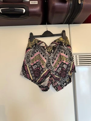 Mönstrade shorts från Odd Molly - Snygga shorts från Odd Molly med färgstarkt mönster i svart, rosa, gul och grå. De har en loose passform och är tillverkade i ett mjukt bomullstyg. Perfekta för varma sommardagar när du vill sticka ut lite extra. Storlek 1 som enligt deras storleksguide motsvarar en storlek S. Fin men det kan finnas små tecken på användning. Kanske något lite tråddraning. 