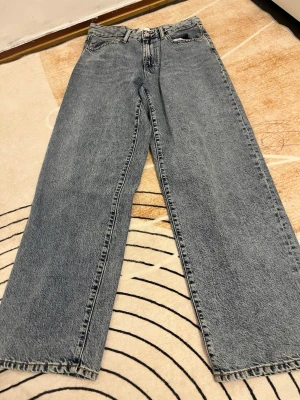 Blå raka jeans från Gina tricot - Säljer ett par klassiska blå jeans från Gina tricot med rak passform och hög midja. Jeansen har fem fickor och är tillverkade i slitstarkt denimtyg. Perfekta för dig som gillar en tidlös och chill stil.