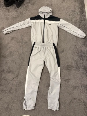 Lacoste tracksuit/dress - Ljusgrå med vita och svarta detaljer i storlek S, kom privat så skickar jag mer bilder samt bilder hur den sitter på en