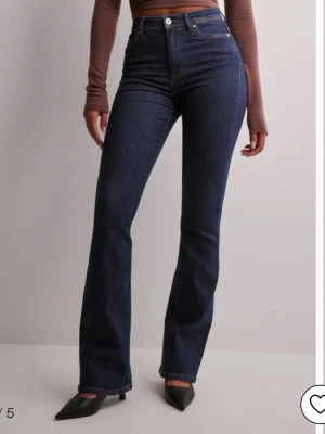 Mörkblå bootcut jeans från Only - Snygga mörkblå jeans från Only med bootcut-snitt och hög midja. Klassisk femficksmodell med knapp och dragkedja framtill. Jeansen är tillverkade i stretchigt denim som sitter bekvämt och framhäver siluetten. Perfekta för dig som gillar en tidlös look.