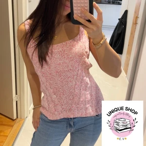 Rosa stickad linnetopp - Säljer en rosa stickad linnetopp med breda axelband och ribbad kant vid halsringningen. Toppen har ett snyggt kabelstickat mönster framtill och är perfekt för varma dagar. Den är mjuk och har en ljus rosa ton som ger en fräsch look till jeans eller kjol.