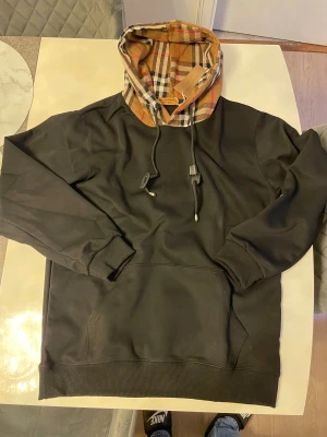Svart burberry hoodie med luva  - Helt ny tröja samt oanvänd, har ett fint Burberry mönster på luvan med skönt material. Passar storlek M och L 