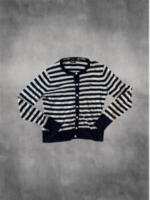 Randig kofta från Polo Ralph Lauren - Snygg randig kofta från Polo Ralph Lauren i marinblått och vitt. Tillverkad i mjuk pima bomull, med långa ärmar, rund hals och knäppning framtill. Klassisk röd logga broderad på bröstet och ribbade muddar vid ärmslut och nederkant. Inga defekter på tröjan och är i väldigt bra skick. Kontakta vid minst funderig//Nordic closet