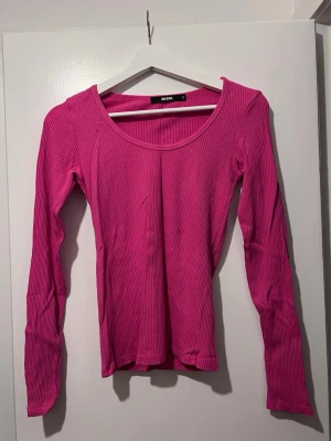 Ribbad rosa långärmad topp Bik Bok - Säljer en ribbad långärmad topp från Bik Bok i en stark rosa färg. Toppen har rund halsringning och är figurnära i modellen. Perfekt att styla med jeans eller kjol för en cool och enkel look.