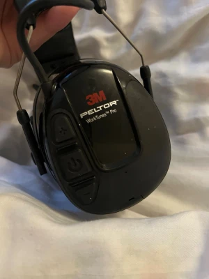 Peltor WorkTunes Pro - 3M Peltor WorkTunes Pro hörselskydd med inbyggd radio. Robust design, bekväm vadderad bygel och stora kåpor för bra ljudisolering. Synliga knappar för volym och ström. Mindre ytliga repor, annars i gott skick. Perfekt för arbete i bullriga miljöer. Nypris 3000 kr 