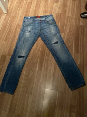 Blå slitna jeans från Jack & Jones - Säljer ett par blå jeans från Jack & Jones med snygga slitningar och hål på. Säljer dess pga att jag ej använder de längre.Hör av dig om du har några frågor