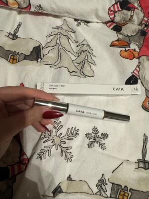 CAIA Double Take Eye Pen FROM AM - Säljer en CAIA Double Take Eye Pen i färgen FROM AM. Pennan har en stilren vit design med silverfärgat lock och kommer i originalförpackning. Perfekt för att skapa skarpa och snygga linjer runt ögonen. Smidig penna som är enkel att använda.