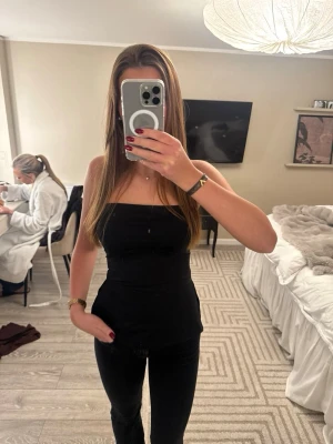 Svart axelbandslös tubtopp - Snygg svart axelbandslös tubtopp med tight passform. Perfekt att styla med jeans eller kjol för en trendig look. Enkel och stilren design som passar till många olika outfits.