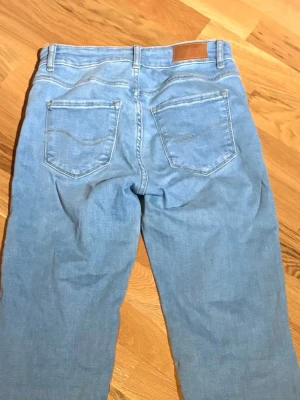 Ljusblå raka jeans i bomull - Säljer ett par ljusblå jeans med klassisk femficksdesign och lite utsvängda ben. Jeansen har normal midja och är tillverkade i mjuk bomull. Perfekta för en avslappnad och stilren look.