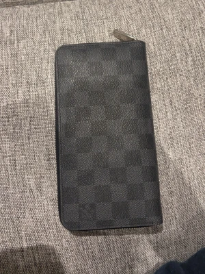 Plånbok känt märke - Säljer en snygg svart plånbok med rutigt monogram som är mycket snyggt och manligt, den är lite avskavt och är väldigt fräsch, dm mig för mer info/ detaljer 