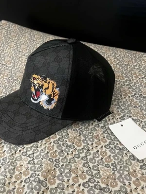 Keps - Svart tiger keps. Bra skick. Skambud kommer att undvikas!