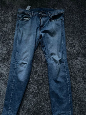 Levi's 511  - Klassiska blå Levi's 511 jeans med smal passform och normal midja. Jeansen har fem fickor, dragkedjegylf och den ikoniska Levi's-lappen bak. Perfekta för en avslappnad och stilren look.