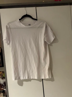 Vit basic t-shirt från 157 - En klassisk vit t-shirt från 157 i 100% bomull. T-shirten har rund halsringning och korta ärmar, perfekt för en enkel och stilren look. Passformen är normal och materialet känns mjukt mot huden.