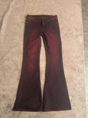 Mörkröda bootcut jeans med flare - Unika mörkröda jeans med bootcut och rejäl flare. Jeansen har klassisk femficksdesign och cool tvätt som ger en vintagekänsla. Perfekta för dig som vill sticka ut med en färgstark look.