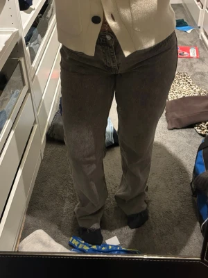 Grå raka jeans med normal passform - Säljer ett par grå jeans med rak passform och klassisk femficksdesign. Jeansen har normal midja och är tillverkade i ett mjukt jeanstyg som är skönt att bära. Perfekta för dig som gillar en avslappnad och stilren look.