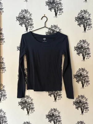 Mörkblå långärmad topp från Lager 157 - En enkel och stilren mörkblå långärmad topp från  Lager 157. Toppen har rund halsringning och är tillverkad i mjuk bomull som känns skön mot huden. Perfekt att matcha med jeans eller kjol för en clean look.