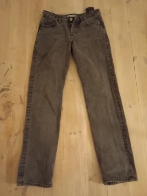 Gråa lågmidjade baggy  jeans i vintage-stil - Snygga gråa jeans med baggy/rak passform och klassisk femficksdesign. Jeansen har en något tvättad look och lågl midja. Perfekta för dig som gillar en avslappnad och tidlös stil.