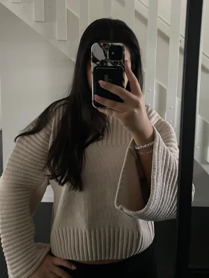 Beige stickad tröja Gina Tricot - Beige stickad tröja från Gina Tricot med breda, utsvängda ärmar och ribbad struktur. Tröjan har en avslappnad passform och är perfekt för lager-på-lager-stil. Mjuk och skön känsla, passar till många outfits. Tröjan är endast använd en gång🤍