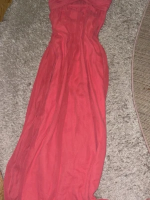 Rosa långklänning från NLY Trend - Säljer en snygg rosa långklänning från NLY Trend i storlek 38. Klänningen är axelbandslös och har en elegant, figurnära passform med svepande kjol. Perfekt för dig som vill sticka ut med en färgstark look.