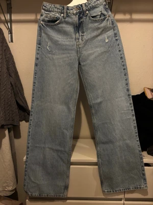 Blå wide high waist jeans från H&M - Säljer ett par ljusblå jeans från H&M med wide passform och hög midja. Klassisk femficksmodell i mjuk bomullsdenim. Perfekta för dig som gillar avslappnad stil och raka ben. Helt nya!!