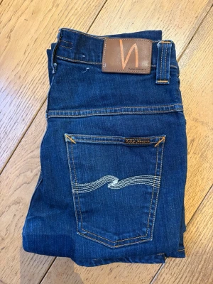 Mörkblå jeans från Nudie Jeans - Säljer ett par riktigt feta Nudie jeans av modellen Thin Finn som är i nyskick. Sjukt bra passform och de är W31 som står i byxorna. De är L32 i längd. Riktigt feta och mycket fräscha. Hör av er vid frågor.