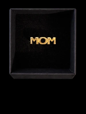 Guldfärgad ring med texten MOM - Stilren ring i guldfärgad metall med texten MOM. Perfekt accessoar för att visa uppskattning till någon speciell. Kommer i en elegant svart ask och har en enkel, modern design.