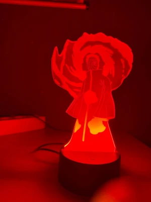 Naruto LED-lampa cosplay accessoar - Cool LED-lampa med motiv av Tobi från Naruto, perfekt som accessoar till cosplay eller maskerad. Lampan kan lysa i olika färger, bland annat rött och gult. Tillverkad i akryl och plast med svart bas och USB-anslutning.