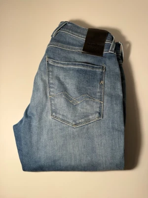 Replay Hyperflex ljusblå jeans - Snygga ljusblå jeans från Replay Hyperflex med klassisk femficksdesign och diskreta sömmar på bakfickan. Jeansen har en modern passform och är tillverkade i stretchigt denim för extra komfort. Perfekta för en avslappnad och trendig look.