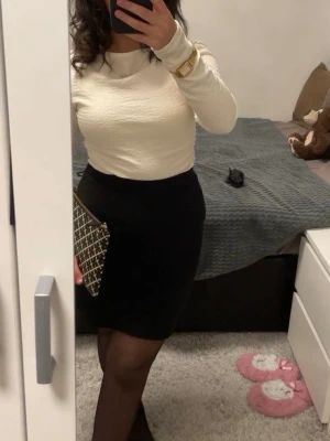 Snygg svart basic pennkjol – Petite XS - Superfin svart kjol i tight modell som sitter riktigt snyggt på kroppen 🤍 Perfekt till både vardag och fest – funkar lika bra med en stickad tröja som med en topp & klackar.   Obs! Det finns ett synligt streck/söm baktill på kjolen (se tredje bilden), inget som påverkar användning men viktigt att veta innan köp.  Minimal, classy och lätt att styla – en riktig wardrobe essential ✨