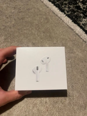 Apple AirPods trådlösa hörlurar - Säljer ett par vita Apple AirPods i originalförpackning. Snygg och stilren design med rundade former och minimalistiskt utseende. Perfekta för dig som vill ha smidiga trådlösa hörlurar till mobilen eller datorn.