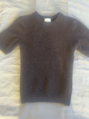 Mörkbrun stickad tröja kort ärm -  mörkbrun stickad tröja med korta ärmar och rund halsringning. Tröjan har en enkel, klassisk design och ribbstickade muddar vid ärmslut och nederkant. Perfekt för lager på lager och passar till det mesta. aldrig använd. köpte för 200kr