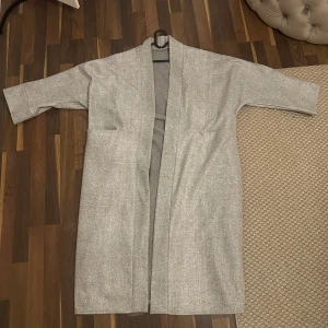 OVERSIZED Ljusgrå lång kappa med fickor - Säljer en oversized ljusgrå kappa, är 163 cm och köpte jackan i frankrike. Säljer den för 200kr, har aldrig använt den! 