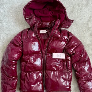 Jacka från Nelly - oanvänd  - Säljer en oanvänd Everyday Shiny Puffer Jacket från Nelly, vinröd, storlek XXS. Nypris är 799, mitt pris 600. Om jackan: Vadderad jacka från Nelly Rak, något kortare modell Glansigt material Avtagbar huva med fleece-foder och dragsko Tvåvägsdragkedja på framsidan Fickor på sidorna med tryckknapp Dragsko i nederkant Resår vid ärmsluten https://nelly.com/se/produkt/nelly-everyday-shiny-puffer-jacket_249718-0047/