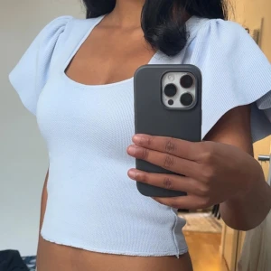 Ljusblå topp med puffärmar från ONLY - Superfin ljusblå topp från ONLY med fyrkantig ringning och stora puffärmar. Croppad modell i ribbad bomullsmix som ger en snygg och bekväm passform. Perfekt att styla med jeans eller kjol för en trendig look.