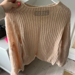 Beige ribbstickad tröja i ullmix - Supermysig beige stickad tröja med ribbad struktur och lång ärm. Tröjan har en fluffig känsla och är perfekt för kyliga dagar. Passformen är normal och den har en rund halsringning. Snygg att styla med jeans eller kjol för en chill look.