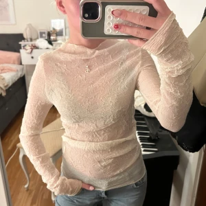 Beige mesh topp från Zara - Säljer en tunn och transparent beige mesh topp från Zara. Toppen har lång ärm, rund halsringning och ett snyggt skrynklat tyg som ger en cool textur. Perfekt att styla lager på lager eller med ett linne under. Superstretchig och sitter tight mot kroppen.