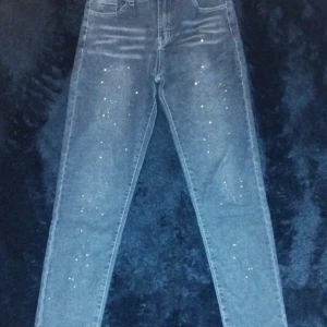 Grå skinny jeans med färgstänk - Snygga grå jeans med skinny fit och coola färgstänk i vitt och gult framtill. Klassisk femficksmodell med hög midja och raka bakfickor. Perfekta för dig som vill sticka ut med en unik detalj i vardagslooken.