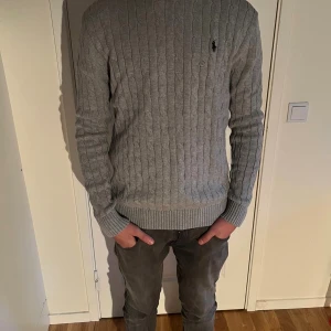 Grå kabelstickad tröja Polo Ralph Lauren - Snygg grå kabelstickad tröja från Polo Ralph Lauren. Storlek S. Tröjan är tillverkad i 100% bomull. Perfekt för dig som gillar stilrena och tidlösa plagg. Kontakta vid mer frågor eller funderingar🙌