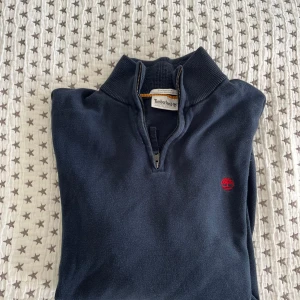 Mörkblå half zip tröja från Timberland - Snygg mörkblå långärmad tröja från Timberland med half zip och hög krage.  Perfekt för dig som gillar stilrena och bekväma plagg. Tröjan är i väldigt fint skick!