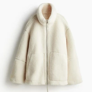 teddyjacka hm - Mysig vit trendig teddyjacka från hm med hög krage och stora fickor framtill. Jackan har en rak, loose passform och stängs med dragkedja. Perfekt för kalla dagar när du vill vara både varm och snygg. Materialet är fluffigt och mjukt, vilket ger en chill vibe.