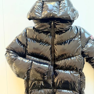 Svart glansig pufferjacka från Colmar -  Jätte fin Colmar jacka endast använd några gånger så i jätte fint skick.  Svart, glansig i stl 172, 16 y ( som en xs ). Nypris 5000 kr, kvitto finns, inköpt vinter 2024.