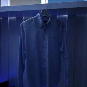 Ljusblå skjorta från GANT - Snygg ljusblå skjorta från GANT med klassisk button-down krage och broderad logga på bröstet. Säljs pga att jag växt ur den.