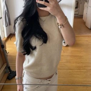 Beige stickad kortärmad tröja H&M - Superfin beige stickad tröja från H&M med korta ärmar och rund halsringning. Enkel och stilren modell som är perfekt till både jeans och kjol. Mjuk och skön kvalitet med ribbade kanter vid ärmslut och nederkant.