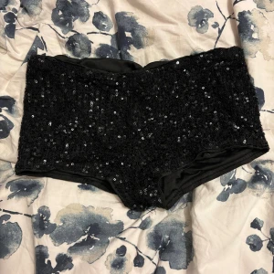 Svarta paljettshorts - Snygga svarta shorts med massor av glittrande paljetter över hela tyget. Modellen har en tight passform som sitter snyggt på kroppen. Perfekta för dig som vill sticka ut och glänsa lite extra.