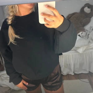 Svart sweatshirt från Nelly - En svart, basic sweatshirt från Nelly i storlek M. Tröjan har en klassisk rund halsringning, ribbade muddar och en loose passform. Perfekt för chill dagar eller när du vill ha en enkel och stilren look.