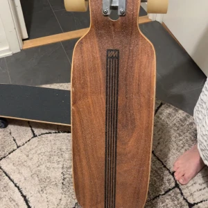 WM Longboard Tekisesu 19-96 - Snygg longboard från WM med Tekisesu 19-96 design. Träfinish med svarta detaljer och japansk grafik undertill. Brädan är i fint skick med endast mindre märken, hjul och trucks ser fräscha ut. Perfekt för cruising och carving, stabil och stilren modell.