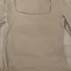Beige långärmad topp med fyrkantig hals - Säljer en stilren beige långärmad topp från H&M i storlek S. Toppen har en snygg fyrkantig halsringning som ger en modern vibe och är gjord i mjuk bomull. Perfekt att matcha med jeans eller kjol för en clean look.
