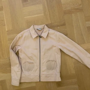 Söt tunn jacka med tryck - Jag säljer en super söt Stella jacka med en ljus rosa färg! Den har ett coolt motiv på ryggen och små snäckor framtill som fickor. Det är en BARN storlek!!!! 10ÅR